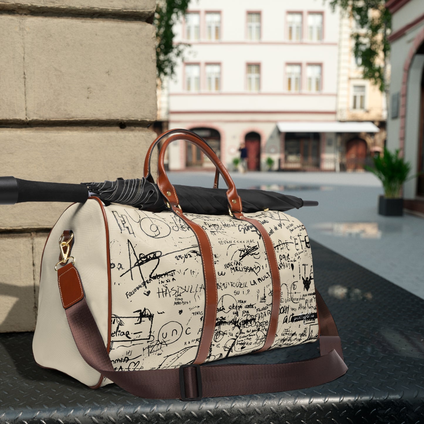 White duffel bag with black text and brown handles and strap on a metal surface outdoors.